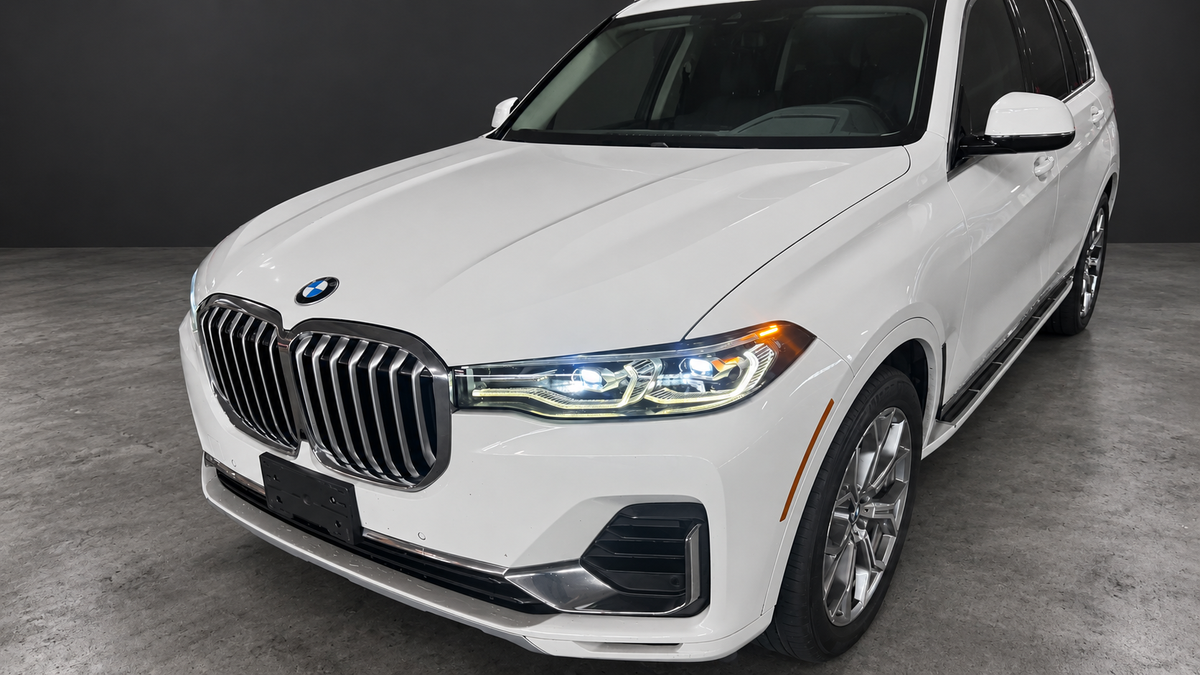 BMW X7 front three-quarter close-up with edited lighting and dark background; original framing preserved.