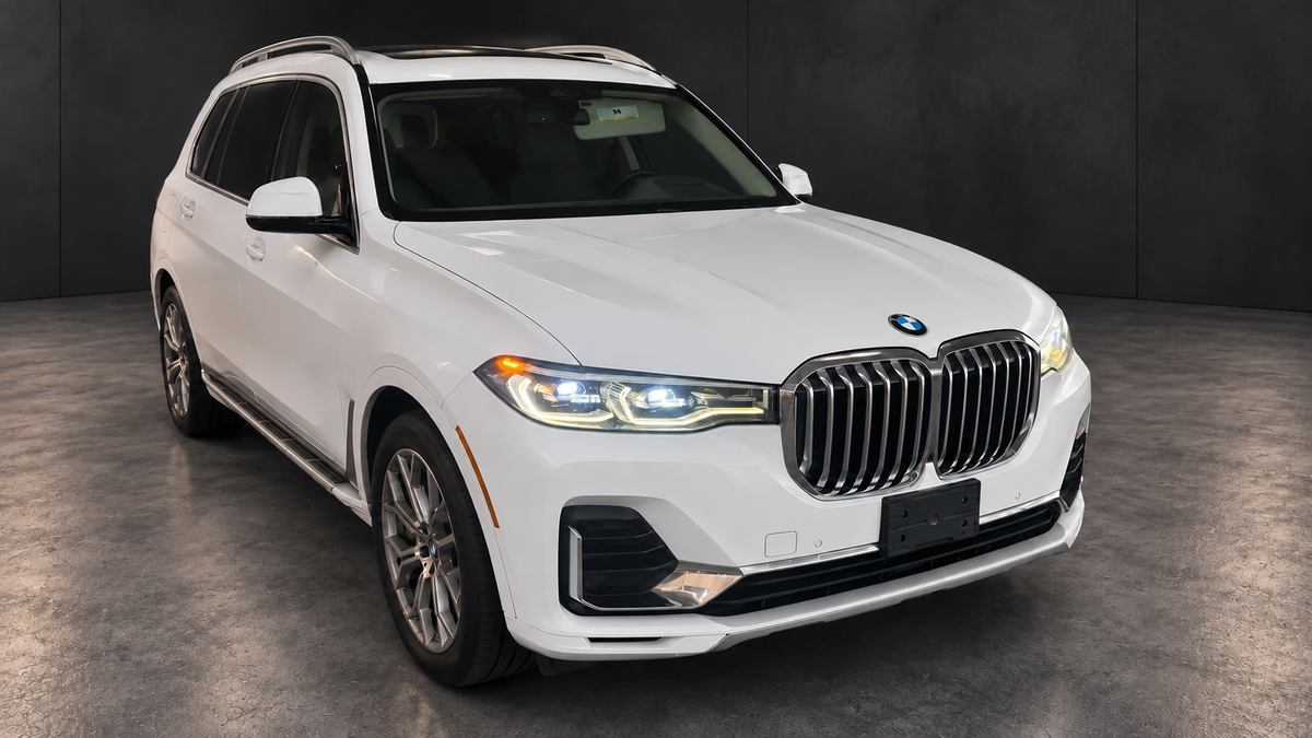 BMW X7 front three-quarter view with edited lighting and dark background.